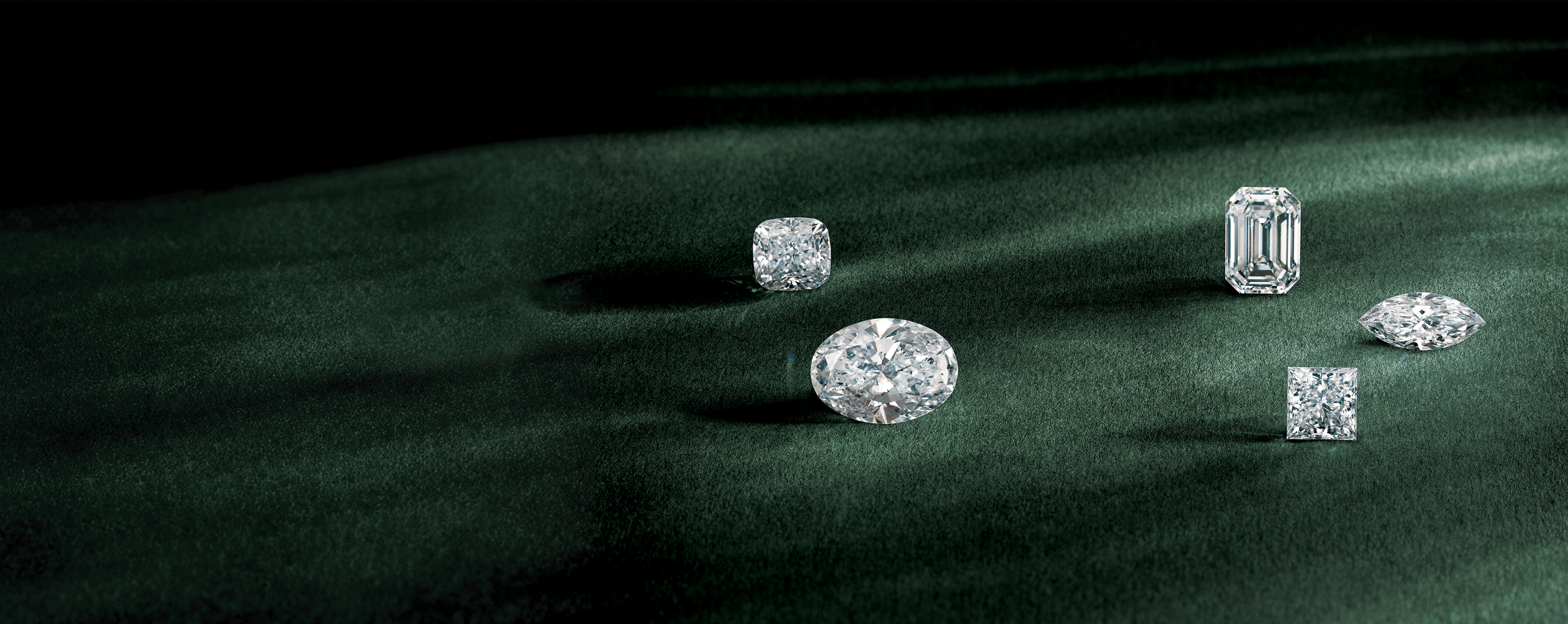 pear emerald princess cushion and marquise cut loose diamonds sitting on a soft green surface